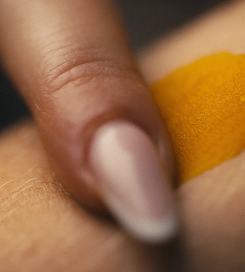 Eine fingerspitze mit einer erbsengroßen menge goldenem balsam