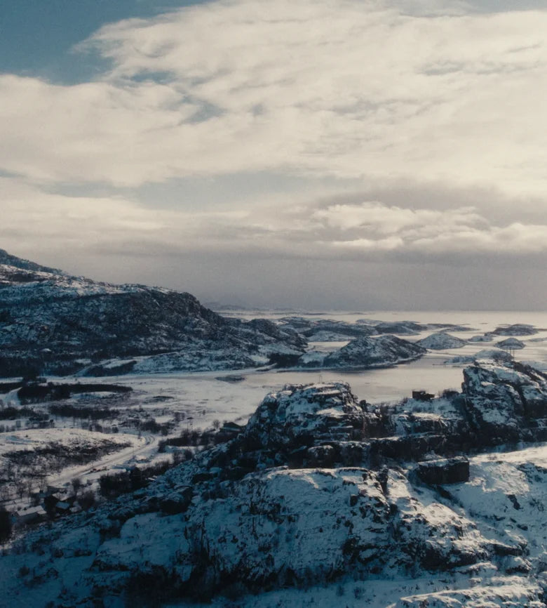 Eine Frau auf einem verschneiten norwegischen Fjord mit einem Frøya-Tiegel in der Hand